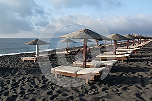 Tanning beds and umbrellas on Perissa beach, Santorini, Greece