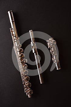 Tansverse flute unmounted into three parts on black table vertical