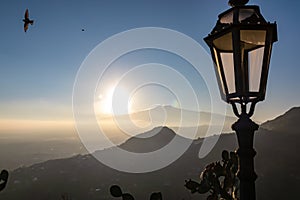 Taormina - Close up view on lantern with panoramic view on volcano Mount Etna from the rooftops of Taormina, Sicily, Italy,