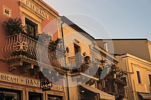 Vintage houses with beautiful decorated balconies by blooming potted flowers, succulents and cacti in Taormina. Sicily