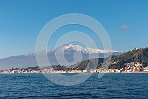 Taormina - Panoramic view from open sea on snow capped volcano Mount Etna in Taormina, Sicily, Italy, Europe, EU.