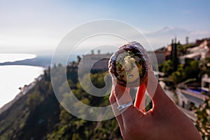 Taormina - Person holding homemade Sicilian Cannoli with view on mount Etna, Taormina, Sicily
