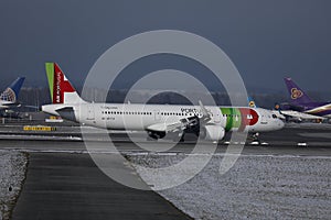TAP Air Portugal plane taxiing on runway in Munich Airport, Germany, Winter time with snow