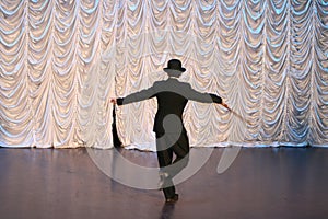 Tap dance with a cane in a black hat. Dance step. A man is dancing on stage