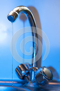 Tap with dripping waterdrop. Water leaking, saving.