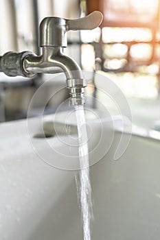 Tap water running wastage from faucet over hand washing sink for saving ecological