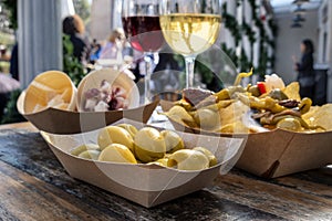 Tapas bar. Olives, potato chips, cheese and jamon, red and white wine, on a wooden table