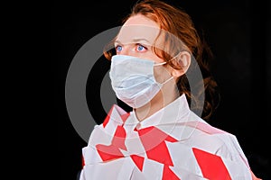 Tape-bound woman with painful eyes in a protective mask on a dark background, profile portrait. Close-up of a red-haired girl in a