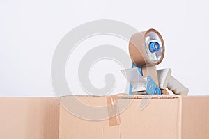 Tape dispenser sealing a shipping cardboard box
