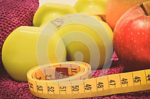 Tape measure, fresh fruits and dumbbells using in fitness. Slimming, healthy nutrition and sporty lifestyles