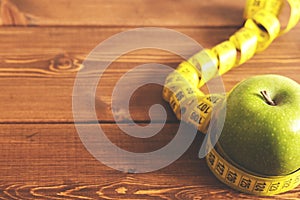 Tape measure and green apple on a wood background top view. The concept of a healthy diet, body weight control, down