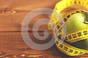 Tape measure and green apple on a wood background top view. The concept of a healthy diet, body weight control, down