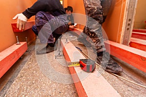 Tape-measure on the wooden block and blurred background with construction workers who working in apartment that is under