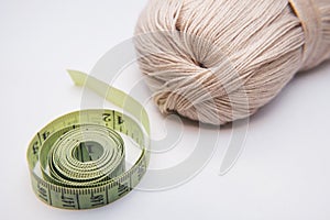 The tape measure and wool are on a white background. Concept picture of clothing production.