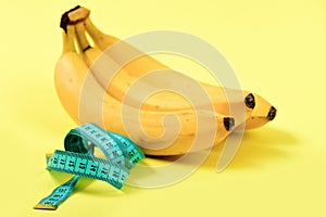 Tape for measuring in turquoise color next to bunch of bananas