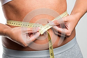 Tapeline measures young woman's waist photo