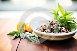 tapenade in a clay dish with a side of fresh basil