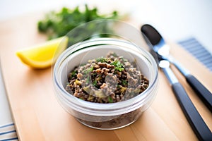 tapenade in a clear container with spreader knife