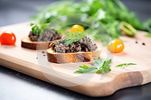 tapenade on crostinis beside fresh herbs on a slate board