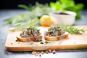 tapenade on crostinis beside fresh herbs on a slate board