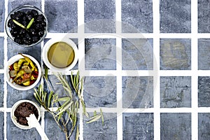 Tapenade - paste made from olives. Bowls with spreadable black and green olive cream and oil on tiles background,