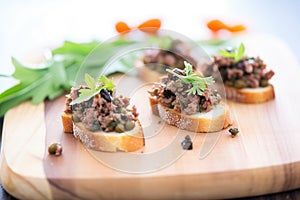 tapenade spread on crostinis on rustic wooden board