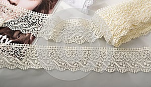 Tapes of ecru white guipure, beauty silk lace fabric on light background