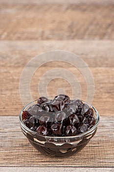 Tapioca Pearl , Bubble topping for tea or other beverage, in a cup, place on wooden table. Copy space