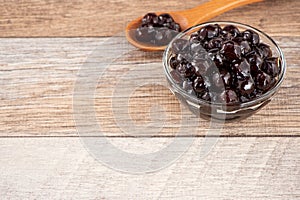 Tapioca Pearl , Bubble topping for tea or other beverage, in a cup, place on wooden table. Copy space