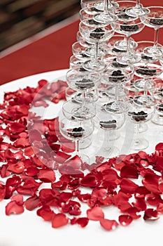 Tapioca pearls in champagne glass pyramid tower decorated with rose petals on white cloth table