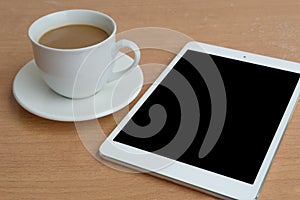 Taplet with black screen and coffee cup on wooden desk