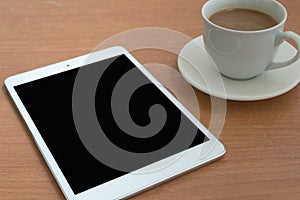 Taplet with black screen and coffee cup on wooden table