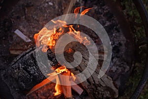 A Close up shot of wood burning in an outdoor fire pit with flames