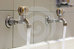 taps with water coming out of the sink and the soap dispenser