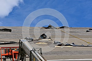 Tar paper on a roofing project is being ripped away by strong winds. photo