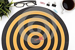 Target arrow hitting on bullseye over office desk table