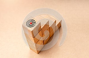 Target dart icon on top of wooden blocks graph steps on brown kraft paper background, top view. Business target, growth process,