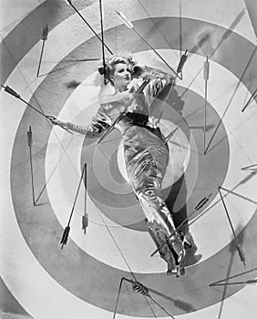 A target of desire, a young woman lying on the bulls eye with arrows around her