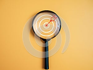 Target, objective, Goal achievement, Purposefulness concept. Magnifying glass focus on dartboard icon over yellow background photo