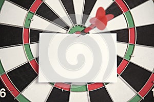 Target red arrow and paper note on center of dartboard.