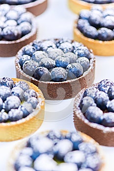 Tarlets dessert from pistachio and chocolaty bakery dough with blueberry decoration photo