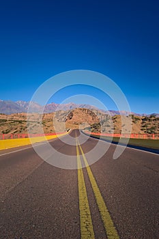 Tarmac road across the desert by the Andes Mountains in Mendoza, Argentina