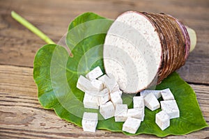 Taro root with half and slice cubes on taro leaf and wooden background, Fresh raw organic taro root ready to cook