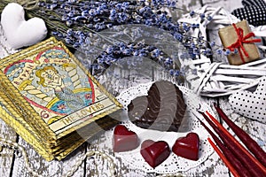 Tarot card Lovers, chocolate candies, heart and love symbols, lavender flowers, candles