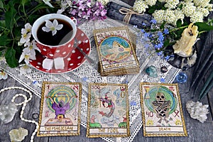 Tarot cards with cup of tea, flowers and black candles on planks