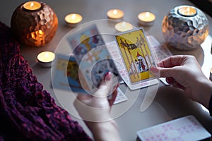 Tarot reader picking tarot cards near burning candles.