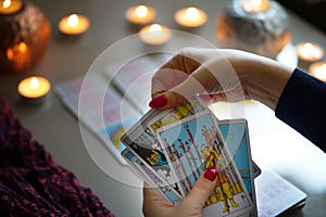 Tarot reader picking tarot cards near burning candles.