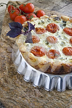 Tart with cherry tomatoes and cheese on aluminum baking dish