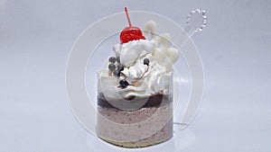 Tart with vanilla cream and tiramisu decorated with chocolate chips and red cherries on a white background