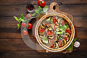 Tart with vegetables. Homemade savory tart with eggplant, zucchini, tomatoes, garlic, mozzarella cheese and fresh basil. Mediterra